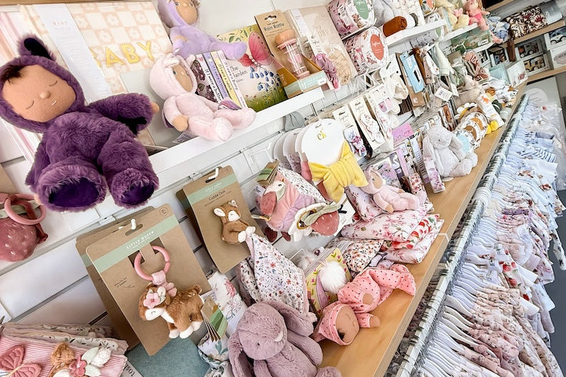 Display of plush toys and baby items on a wooden shelf and baby fashion