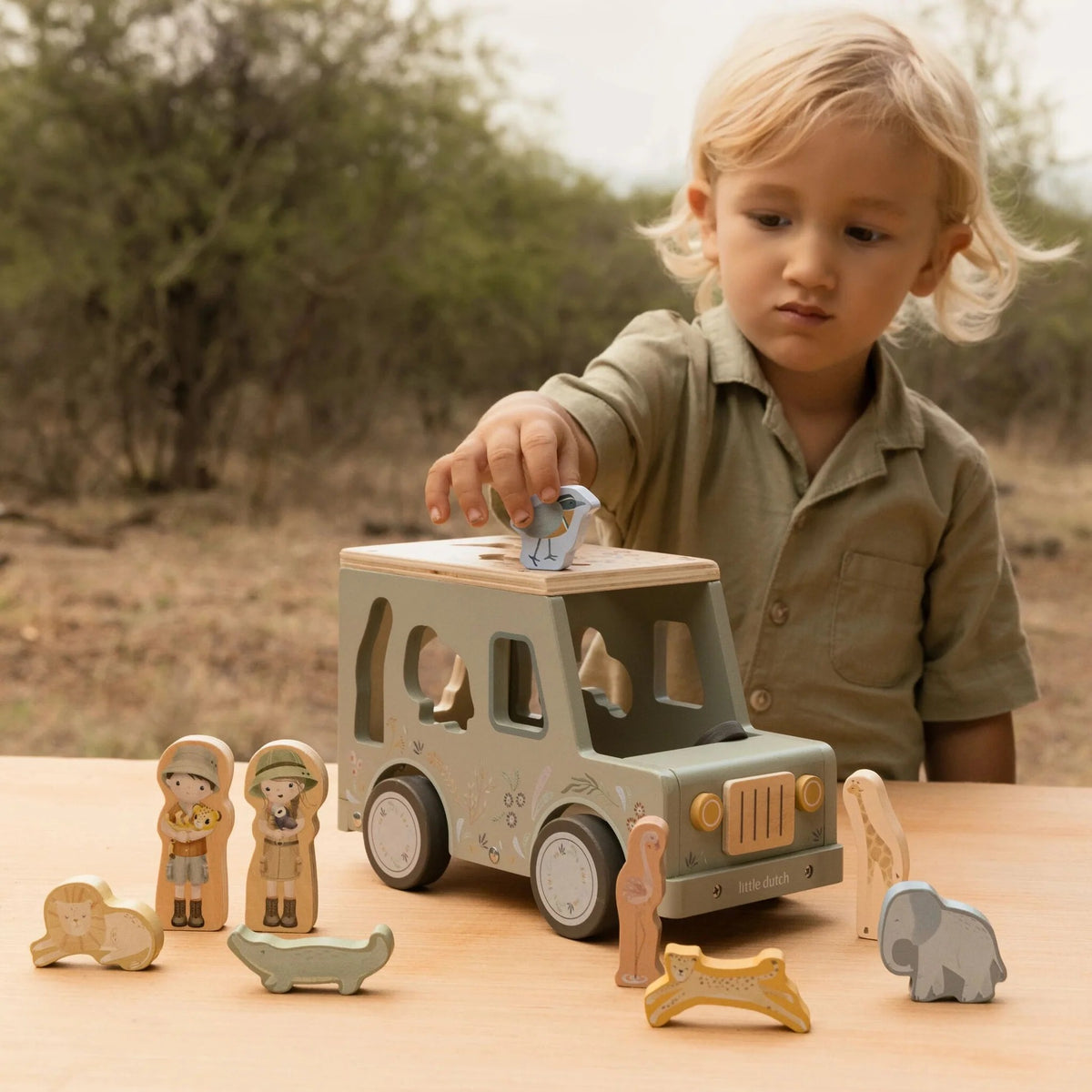 Child placing a wooden piece into the Safari Friends Shape Sorter Safari Car